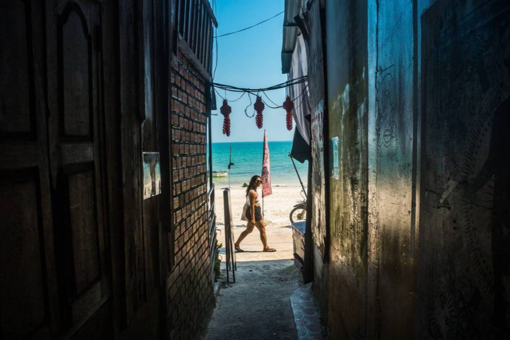 Una turista cammina sulla spiaggia di Koh Rong con vista da un piccolo vicolo